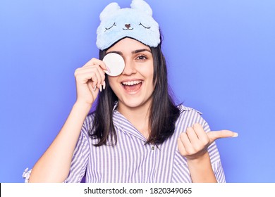 Young Beautiful Girl Wearing Funny Sleep Mask Using Makeup Remover Cotton Pointing Thumb Up To The Side Smiling Happy With Open Mouth 