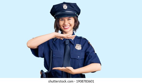 Young beautiful girl wearing police uniform gesturing with hands showing big and large size sign, measure symbol. smiling looking at the camera. measuring concept. 