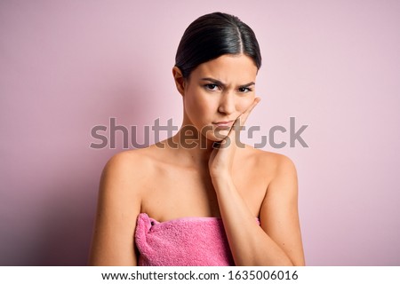 Young beautiful girl wearing towel shower after bath standing over isolated pink background thinking looking tired and bored with depression problems with crossed arms.