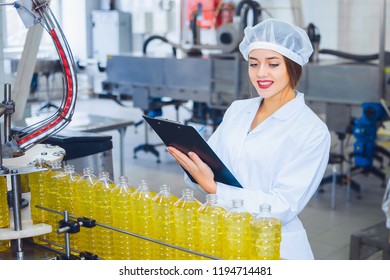 Young beautiful girl in white overalls with a tablet in her hands at a plant for the production of sunflower and olive oil. Quality control in production - Powered by Shutterstock