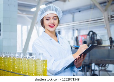 Young beautiful girl in white overalls with a tablet in her hands at a plant for the production of sunflower and olive oil. Quality control in production - Powered by Shutterstock