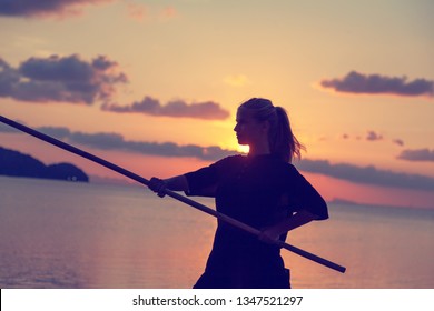 Young Beautiful Girl Woman Blond Doing Kung Fu With Bamboo Stick On The Seashore At Sunset