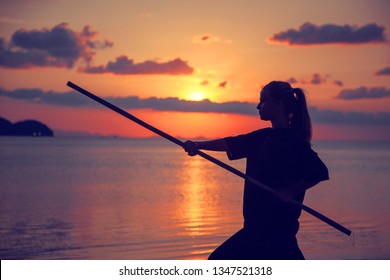 Young Beautiful Girl Woman Blond Doing Kung Fu With Bamboo Stick On The Seashore At Sunset