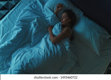 Young Beautiful Girl Or Woman Sleeping Alone In Big Bed At Night, Top View, Blue Toned.