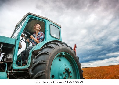 Young beautiful girl working on a tractor in the field, unusual work for women, gender equality concept - Powered by Shutterstock