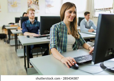Young beautiful girl working on a computer in a classroom with her classmates in the background