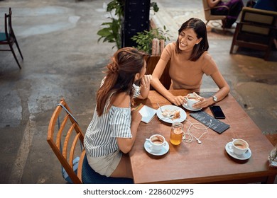 Young beautiful girlfriends having coffee at cafe. Chatting with each other and laughing. Student, hipster, coffee break. - Powered by Shutterstock