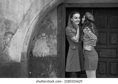 Young beautiful girls dressed in retro vintage style enjoying the old european city summertime lifestyle. Chatting in the street. Black and white. - Shutterstock ID 2185555629