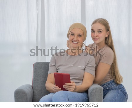 A young and beautiful grateful daughter helping to arrange head scarf to encourage her mother's cancer patient and fortifies her to fight during the chemotherapy. Love and relationship idea.
