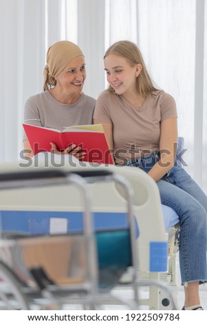 A young and beautiful grateful daughter taking care, reading together and encourage her mother's cancer patient and fortifies her to fight during the chemotherapy.