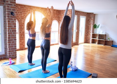 Young Beautiful Group Of Sportswomen Practicing Yoga. Standing Doing Chair Pose At Gym