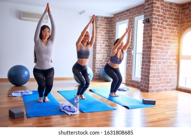 Young Beautiful Group Of Sportswomen Practicing Yoga. Standing Doing Chair Pose At Gym