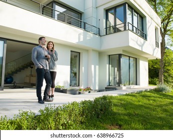 Young Beautiful Handsome Couple Enjoying Morning Coffee In Front Of Their Luxury Home Villa