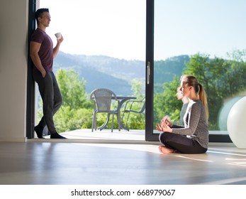 Young Beautiful Handsome Couple Enjoying Morning Coffee And Yoga Exercises On The Door Of Their Luxury Home Villa