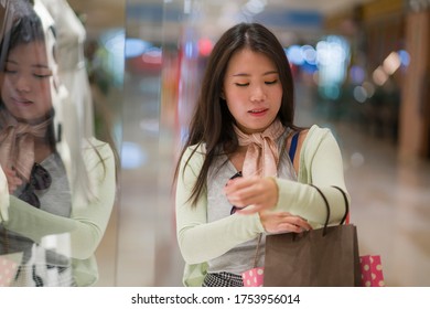 young beautiful and happy Asian buying at shopping mall - young attractive and stylish Japanese woman holding shopping bags at fashion center enjoying sales and discount excited