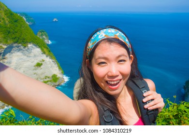 Young Beautiful And Happy Asian Korean Tourist Woman Taking Selfie Picture Smiling Carrying Backpack After Hiking Excursion On Top Of Tropical Sea Cliff Landscape In Holidays Travel Destination