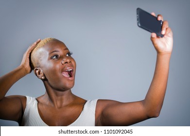 Young Beautiful And Happy Black Afro American Woman Excited Taking Selfie Picture Portrait With Mobile Phone Or Recording Self Portrait Video Posing Showing Proud Her Shaved Head Hair Style