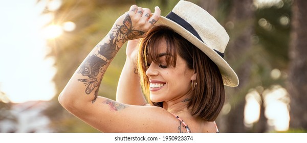 Young Beautiful Happy Brunette Woman Wearing Summer Hat, Smiling Charmingly. Girl With Tattoos. Real People Emotions. Summer, Good Vibes.
