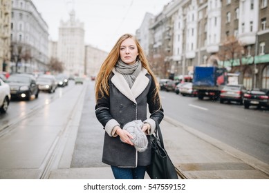 Young beautiful happy smiling girl posing on street. Model playing with her long hair, touching face. Woman wearing stylish clothes. Christmas, New Year, winter holidays concept. Magic snowfall effect