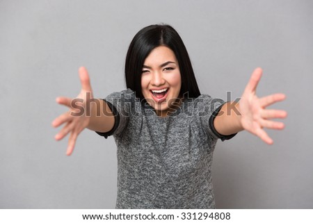 Young beautiful happy smiling in gray jumper looking at camera woman with an open hands ready for hugging