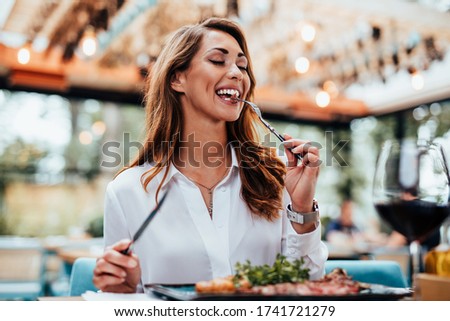 Young beautiful and happy woman enjoying in delicious meal in luxurious restaurant.