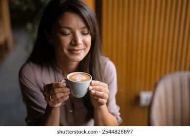 Young beautiful happy woman with long curly hair enjoying cappuccino in a street cafe - Powered by Shutterstock