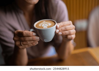 Young beautiful happy woman with long curly hair enjoying cappuccino in a street cafe - Powered by Shutterstock