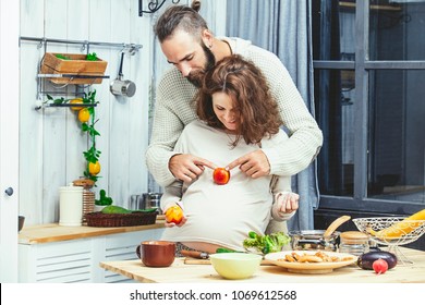 Young beautiful heterosexual couple man and woman lovers pregnant in the kitchen home cook - Powered by Shutterstock