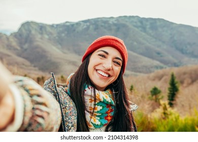 Young beautiful hiker woman taking selfie portrait on the top of mountain - Happy smiling girl using her smartphone - Hiking and climbing cliff - Powered by Shutterstock