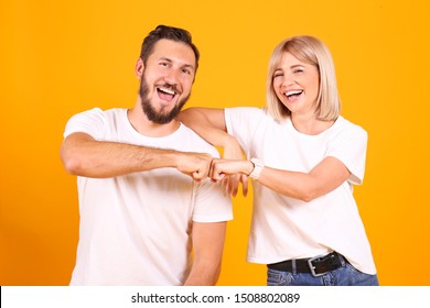 Young beautiful hipster couple having fun posing over isolated yellow background. Portrait of tall man with groomed beard and his short attractive blonde girlfriend. Copy space, close up.