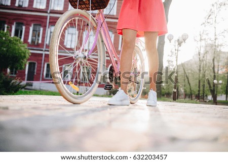 young beautiful hipster woman in pink dress, city vacation, summer trend style, street, riding bicycle, travel, Slim, tanned skin, positive, close-up details of legs, cheerful