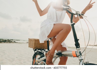 young beautiful hipster woman in white dress, tropical vacation, summer trend style, beach, riding bicycle, travel, Thailand, slim, tanned skin, positive, close-up details of legs, cheerful