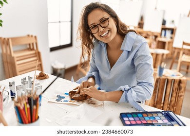 Young beautiful hispanic woman artist smiling confident make ceramic pot with hands at art studio - Powered by Shutterstock