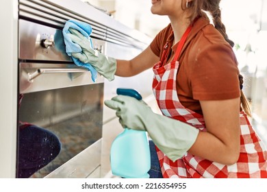 Young Beautiful Hispanic Woman Cleaning Oven Door At The Kitchen