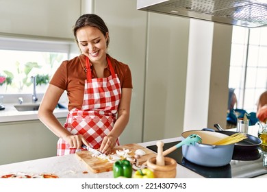 Young Beautiful Hispanic Woman Cooking Spaghetti Cutting Onion At The Kitchen