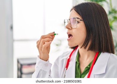 Young Beautiful Hispanic Woman Doctor Taking Pill At Clinic