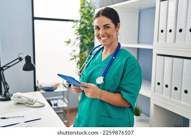 Young beautiful hispanic woman doctor smiling confident using touchpad at clinic - Powered by Shutterstock