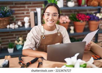 Young Beautiful Hispanic Woman Florist Using Laptop Reading Document At Florist