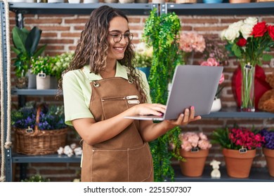 Young beautiful hispanic woman florist smiling confident using laptop at flower shop - Powered by Shutterstock