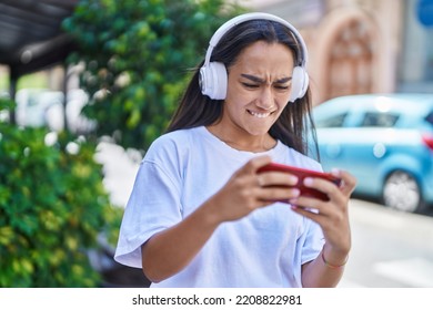 Young Beautiful Hispanic Woman Playing Video Game At Street