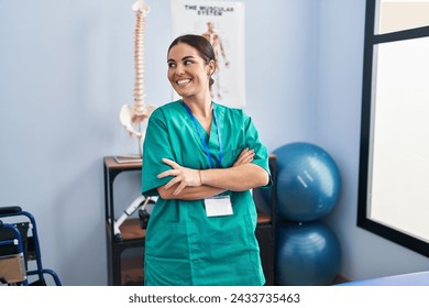 Young beautiful hispanic woman pysiotherapist smiling confident standing with arms crossed gesture at rehab clinic - Powered by Shutterstock