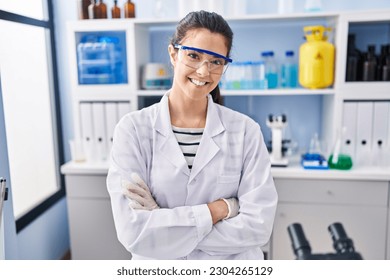 Young beautiful hispanic woman scientist smiling confident standing with arms crossed gesture at laboratory