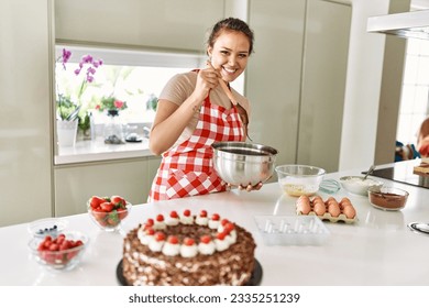 Young beautiful hispanic woman smiling confident mixing chocolate on bowl at the kitchen - Powered by Shutterstock