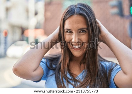 Young beautiful hispanic woman smiling confident relaxed with hands on head at street