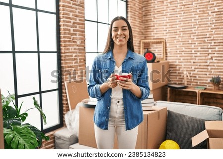 Young beautiful hispanic woman smiling confident drinking coffee at new home