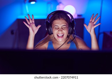 Young Beautiful Hispanic Woman Streamer Playing Video Game With Winner Expression At Gaming Room