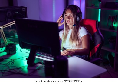 Young Beautiful Hispanic Woman Streamer Playing Video Game With Serious Expression At Gaming Room