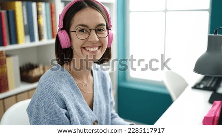 Young beautiful hispanic woman student smiling confident listening to music at library university