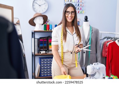 Young beautiful hispanic woman tailor smiling confident cutting cloth at clothing factory - Powered by Shutterstock