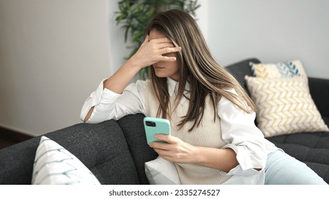 Young beautiful hispanic woman using smartphone with worried expression at home - Powered by Shutterstock